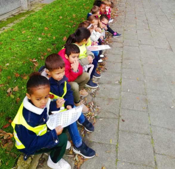 Les tout-petits de Het Pieterke sont assis sur le trottoir avec des feuilles à la main. Ils comptent le trafic.